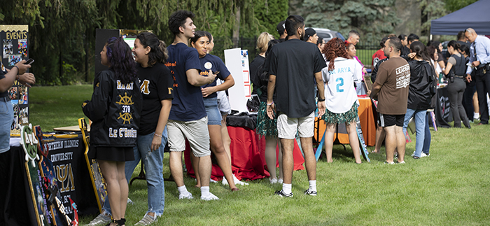 NIU students outside enjoying the Latin Chill event visiting tables and mingling.