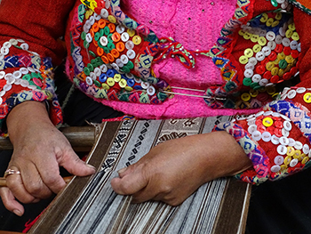 Close up of Peruvian woman practicing traditional weaving techniques.