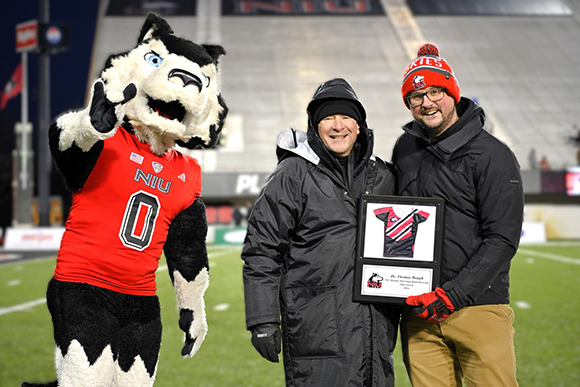 Victor E Huskie, Dr. Thomas Bough and Marty Johnstone pose for a photo on the football field