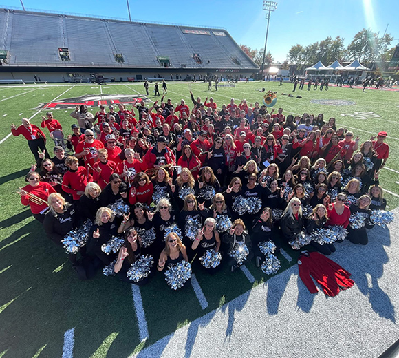 NIU Marching Band and Silverette alumni members pose on the field for a group photo
