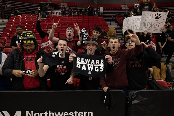 NIU Fans pose and hold up signs for the camera in the seats at the NIU Convocation Center