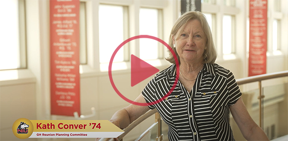 Video thumbnail featuring Kath Conver '74 from the Golden Huskies Reunion Planning Committee, sitting in a well-lit hall with banners in the background.