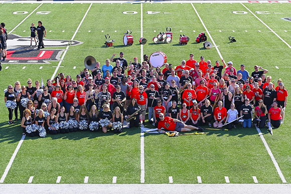 Huskie Marching Band Alumni Network members pose at mid-field for a photo after Fill the Field.