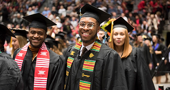 A group of NIU students in graduation caps and gowns at Commencement